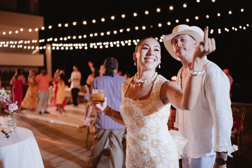 Bride and groom laughing at outdoor wedding reception, Hilton Puerto Vallarta, string lights overhead