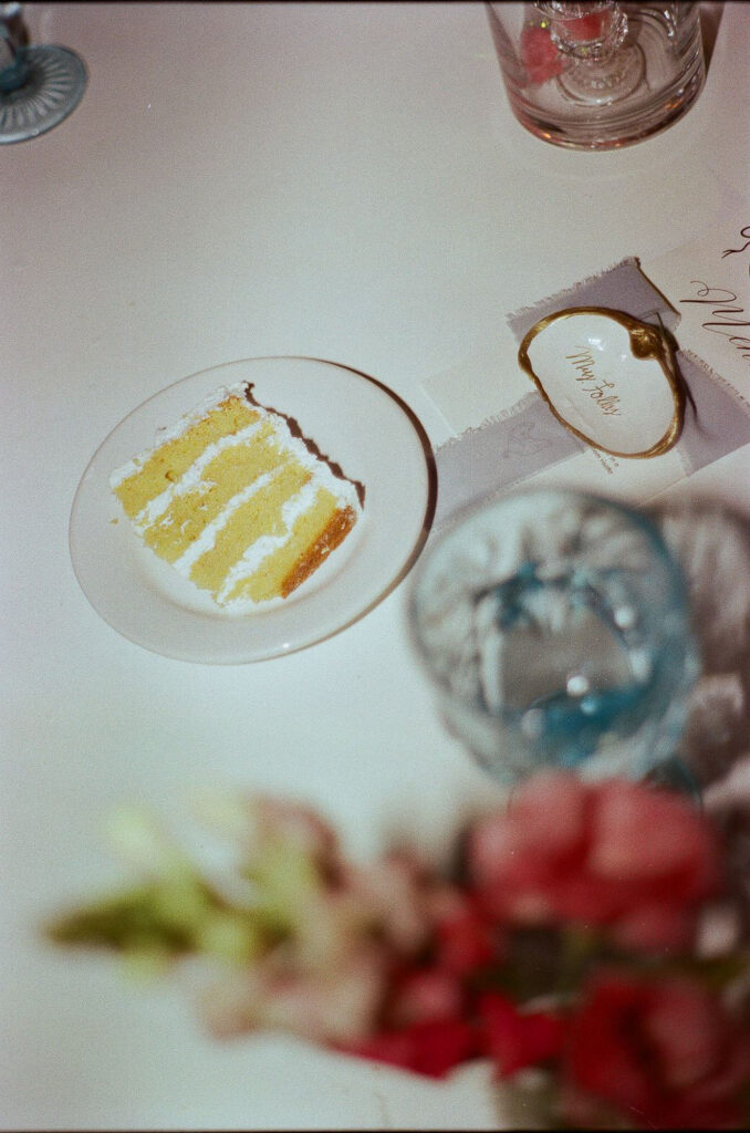 Slice of layered vanilla wedding cake on white plate, Hilton Puerto Vallarta reception, shot on 35mm film