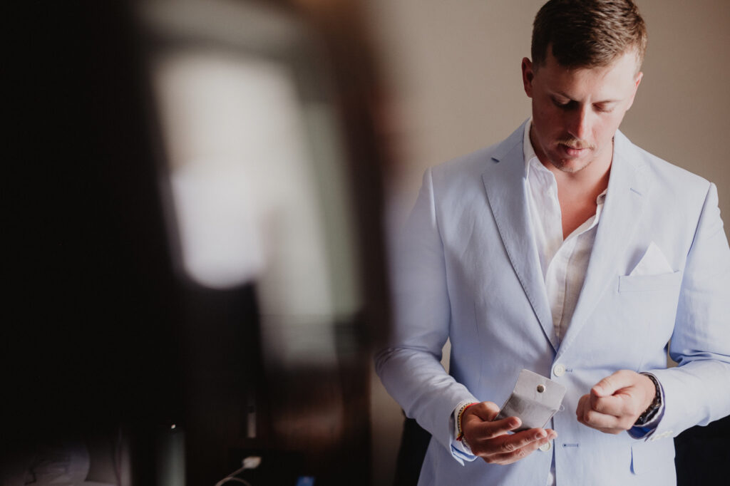 Groom fastening cufflinks before wedding ceremony at Hilton Puerto Vallarta, documentary wedding photography by Alex Obregón