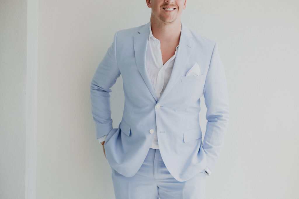 Groom in light blue linen suit smiling at Hilton Puerto Vallarta wedding, documentary style by Alex Obregón
