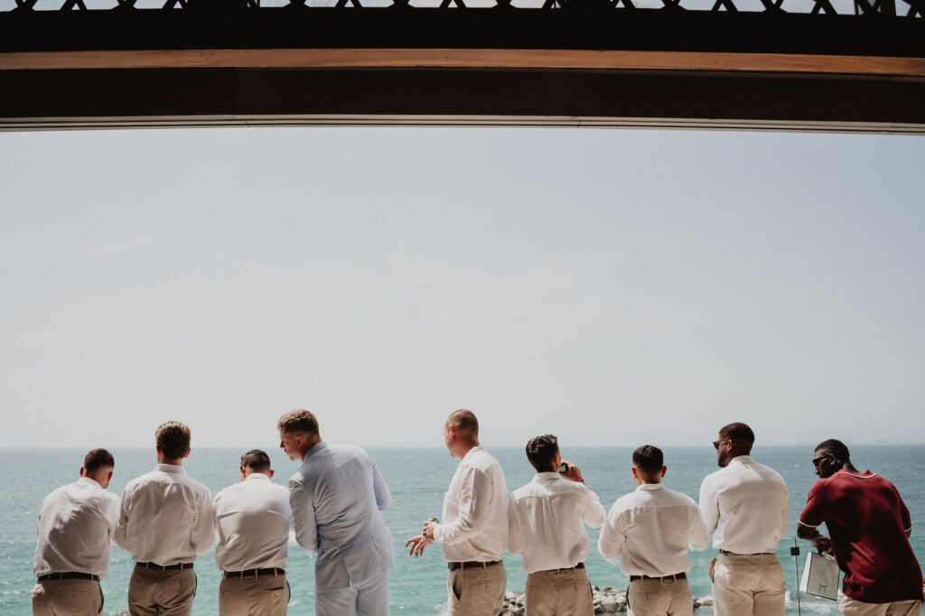 Groomsmen in white shirts overlooking ocean at Hilton Puerto Vallarta wedding ceremony