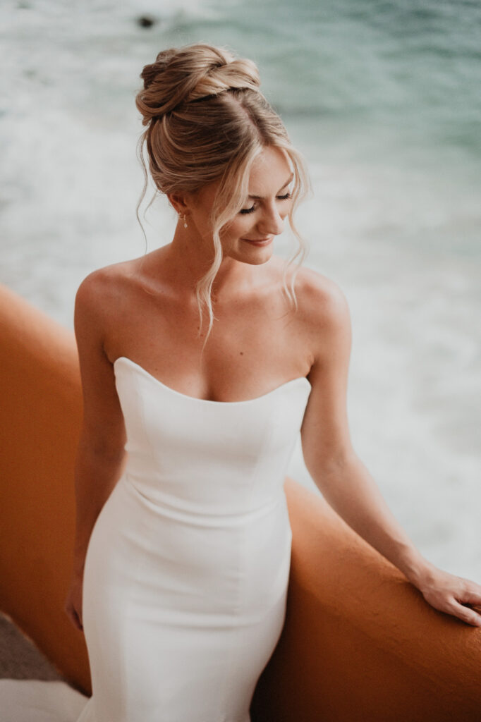 Bride in strapless white gown at Casa Cosmos beach, Puerto Vallarta wedding, ocean waves behind her