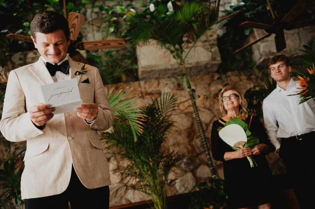 Groom reading vows card and smiling at tropical wedding ceremony, Casa Cosmos Puerto Vallarta