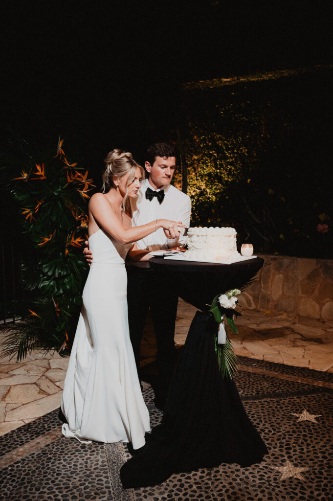 Bride and groom cutting wedding cake at night at Casa Cosmos Puerto Vallarta wedding reception
