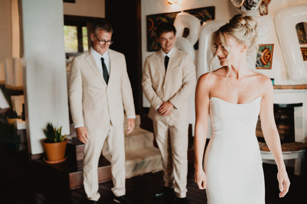 Bride in strapless gown during first look moment with father and brother at Casa Cosmos Puerto Vallarta wedding