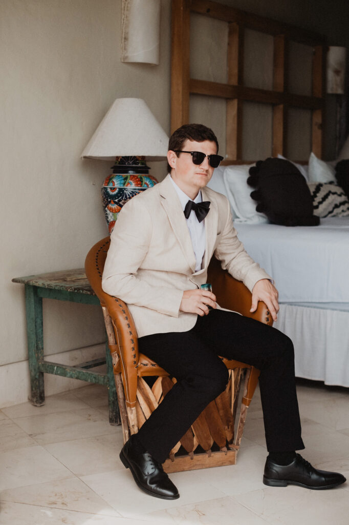 Groom in cream blazer and bow tie seated at Casa Cosmos, Puerto Vallarta wedding photography by Alex Obregón