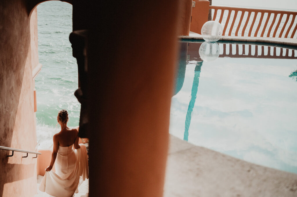 Bride in white gown descending stairs toward ocean at Casa Cosmos, Puerto Vallarta wedding