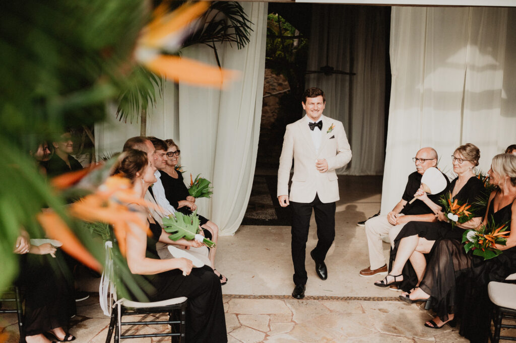 Groom walks down aisle at Casa Cosmos wedding ceremony, Puerto Vallarta, surrounded by bird of paradise flowers