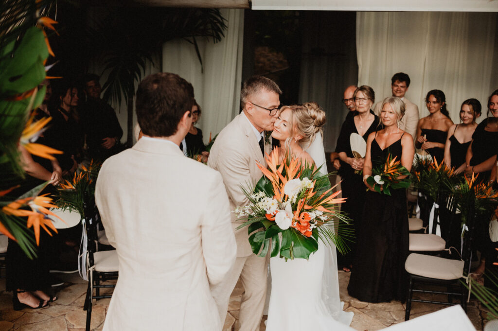 Father kissing bride's cheek at Casa Cosmos wedding ceremony, Puerto Vallarta, tropical bouquet