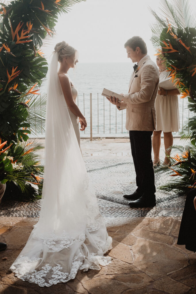 Bride and groom exchanging vows at Casa Cosmos altar with tropical florals and ocean view, Puerto Vallarta wedding