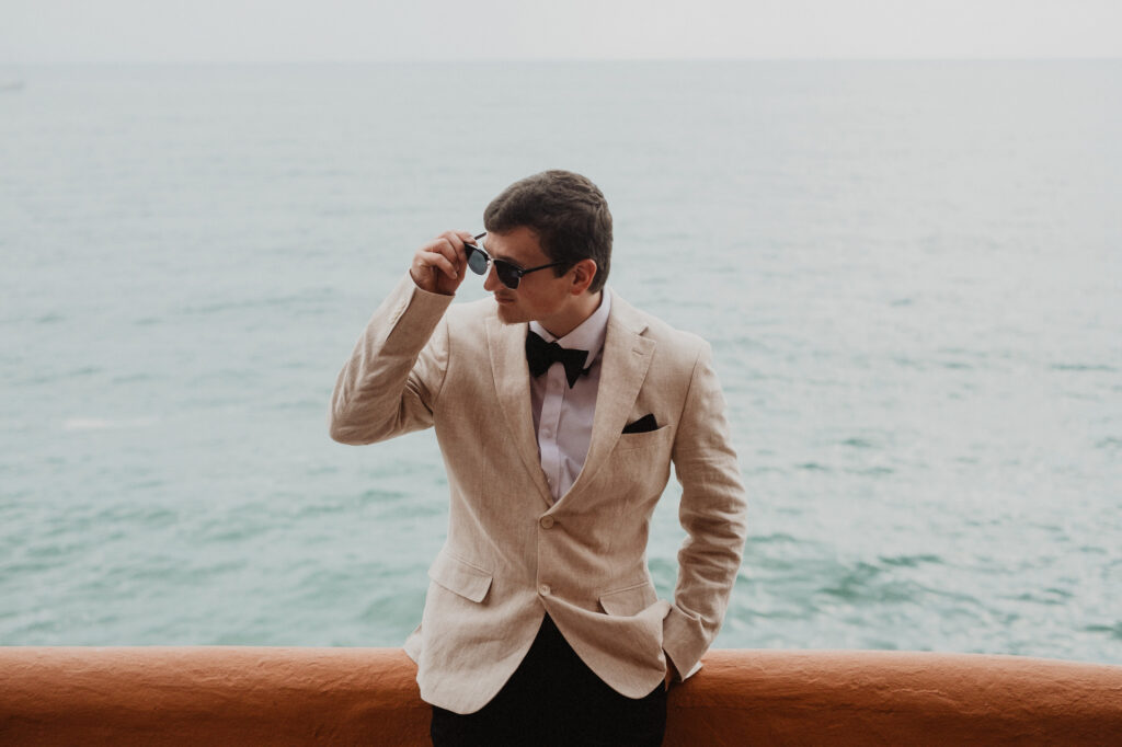 Groom in linen blazer and bow tie adjusting sunglasses at Casa Cosmos, Puerto Vallarta wedding