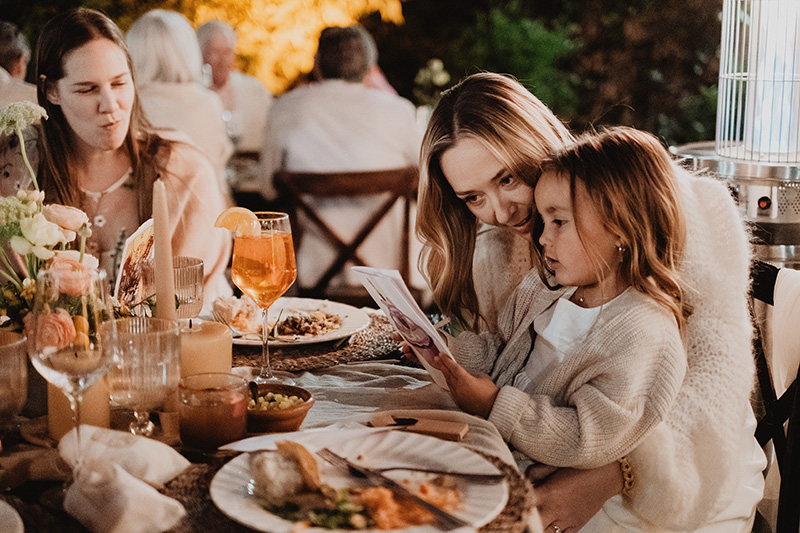 Mother and child reading menu at outdoor wedding reception, San Miguel de Allende, documentary film photography