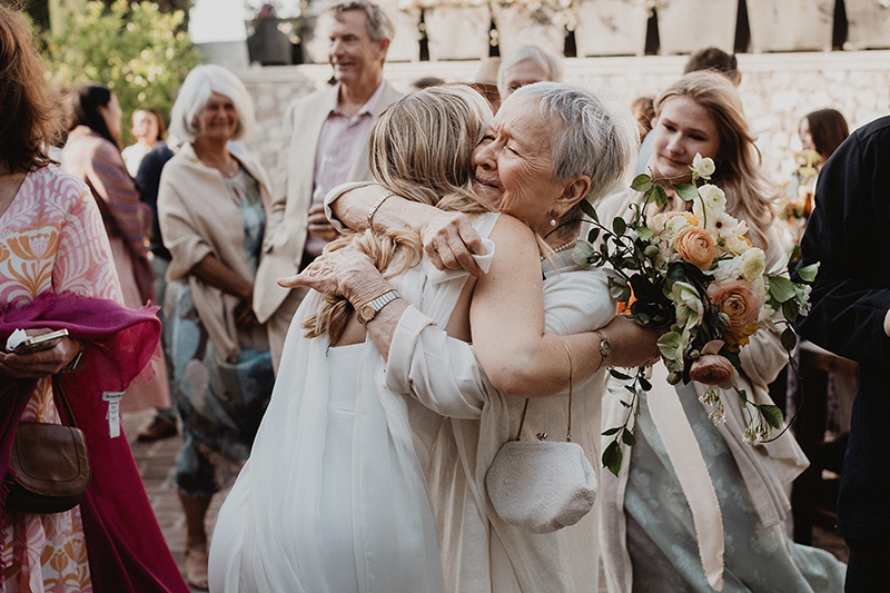 Bride hugging emotional older woman at wedding reception in San Miguel de Allende, documentary photography