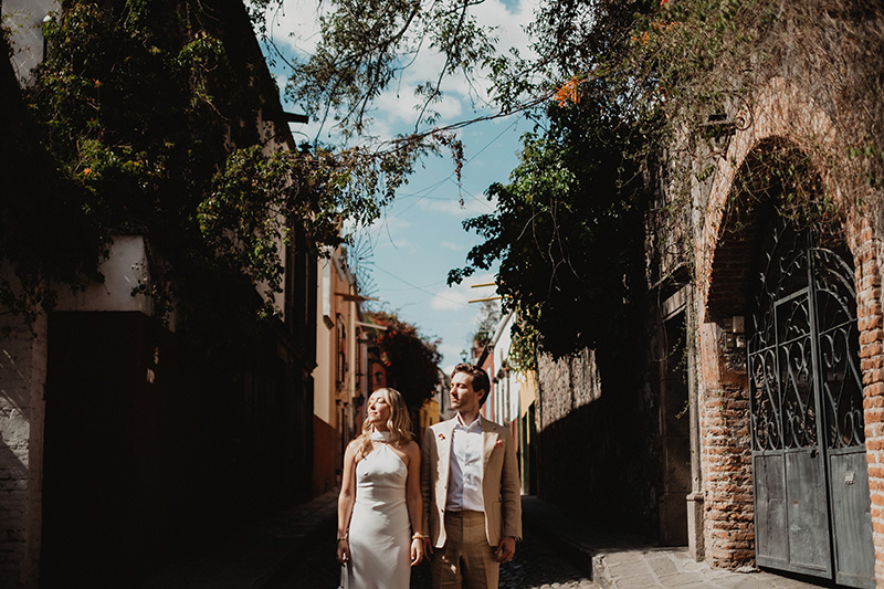 Couple in wedding attire walking cobblestone alley in San Miguel de Allende, documentary wedding photography