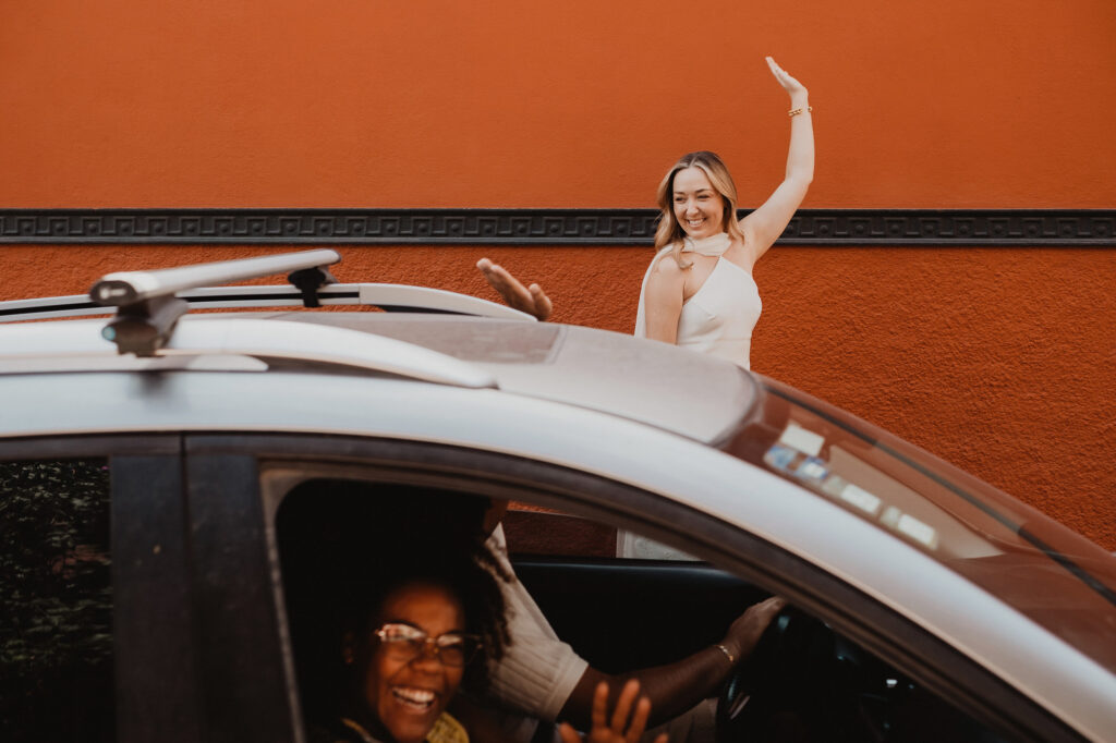Bride waves joyfully outside car at San Miguel de Allende wedding, documentary style
