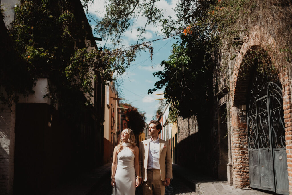 Couple in wedding attire walking cobblestone street in San Miguel de Allende, documentary wedding photo