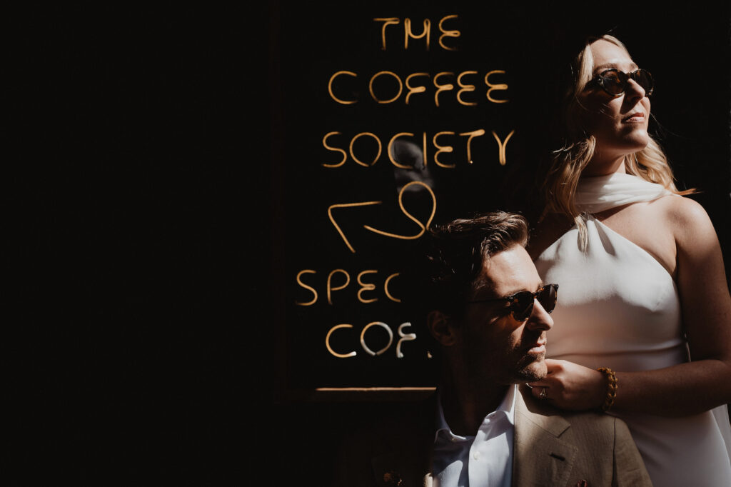 Wedding couple poses by Coffee Society neon sign in San Miguel de Allende, documentary film photography