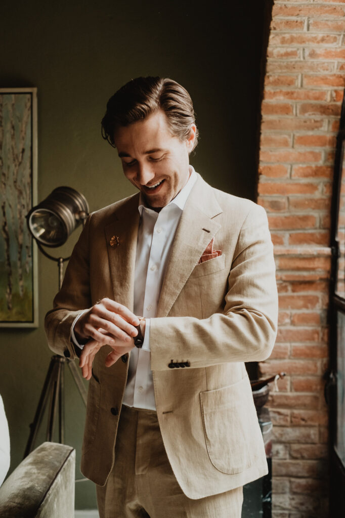 Groom in linen suit adjusting cufflinks before wedding ceremony, San Miguel de Allende