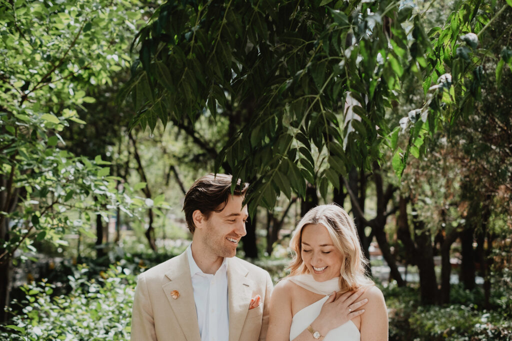 Bride and groom laughing together under lush trees at a San Miguel de Allende wedding ceremony