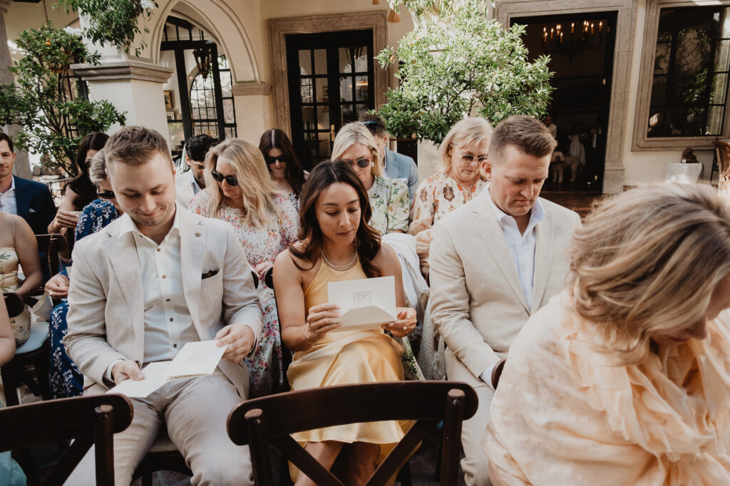 Wedding guests reading ceremony programs at a San Miguel de Allende outdoor ceremony, documentary style