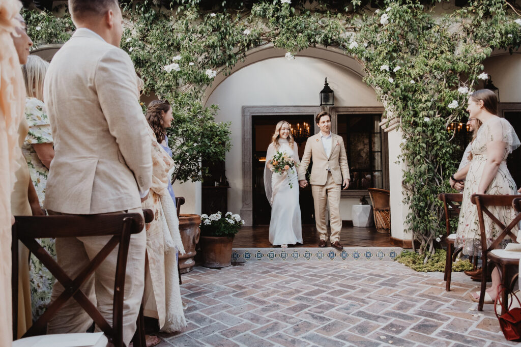 Couple walks hand in hand down the aisle at a San Miguel de Allende wedding ceremony in a floral courtyard