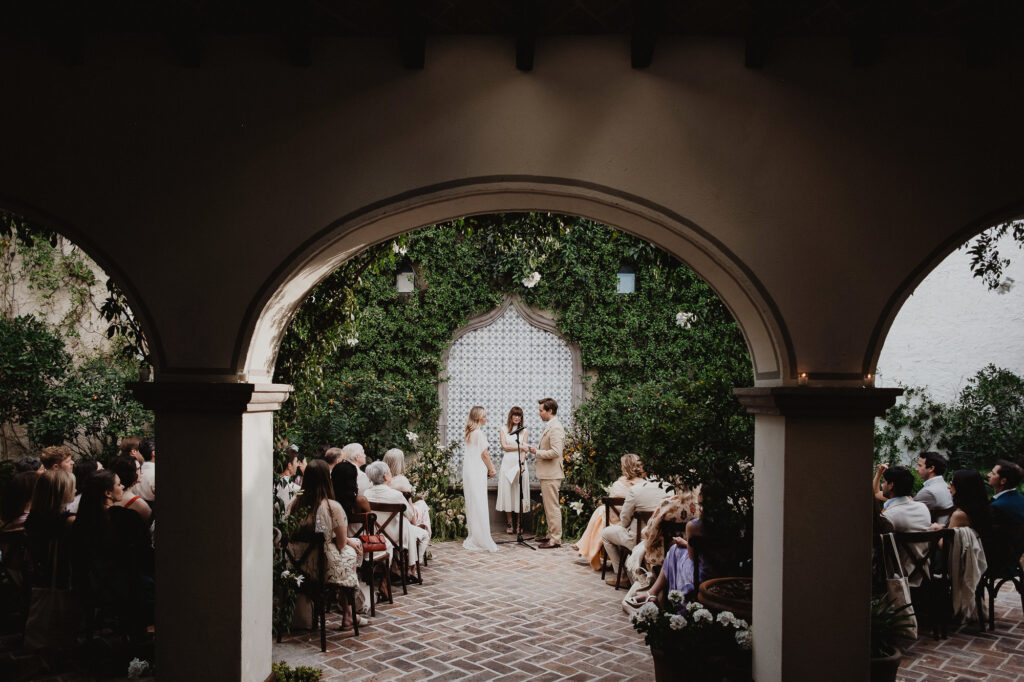 Wedding ceremony in a courtyard in San Miguel de Allende, couple exchanging vows under lush greenery and arches