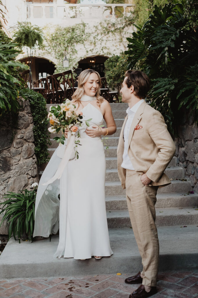 Bride and groom share a quiet moment on stone steps at a San Miguel de Allende wedding, lush greenery surrounding them