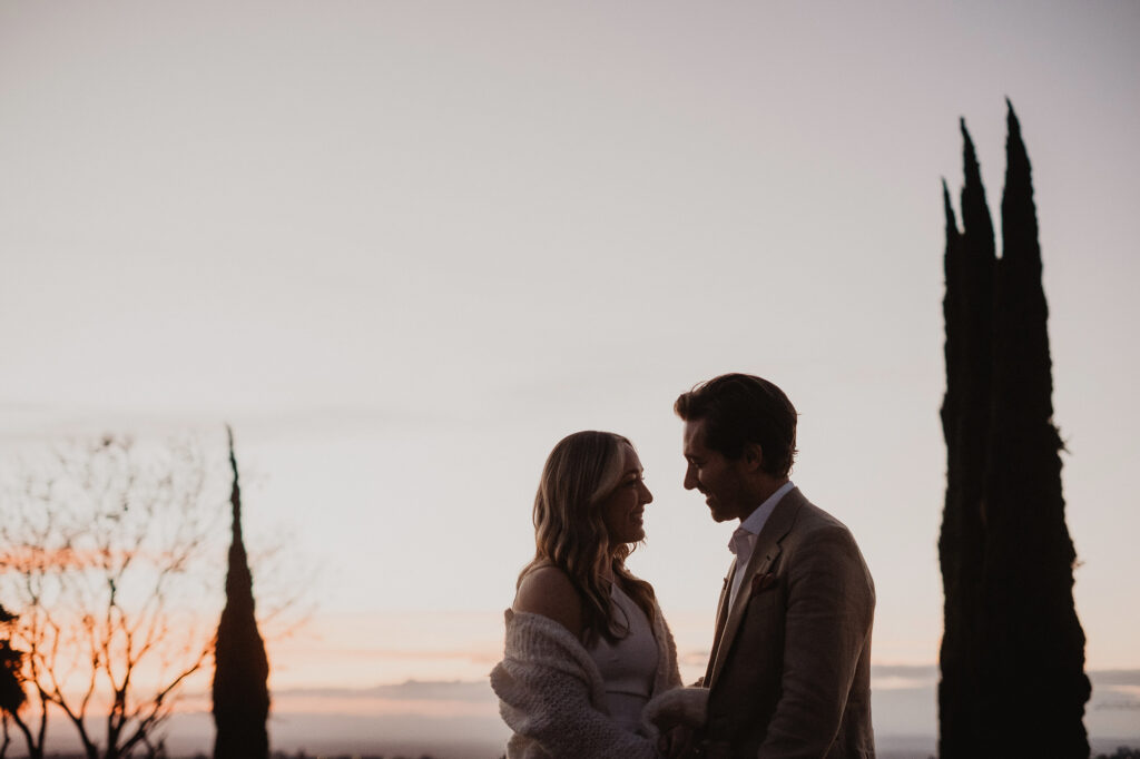 Couple shares a romantic moment at sunset during their San Miguel de Allende wedding ceremony, cypress trees in background