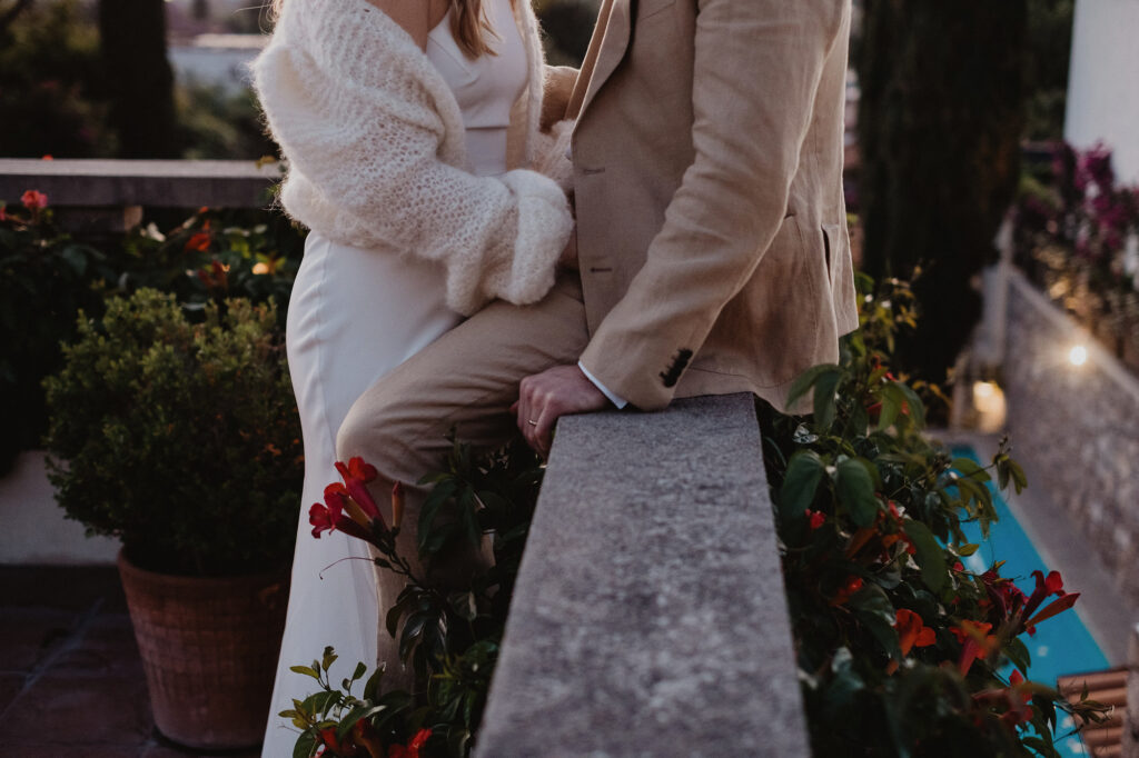 Couple embracing on stone terrace with red flowers, San Miguel de Allende wedding photography