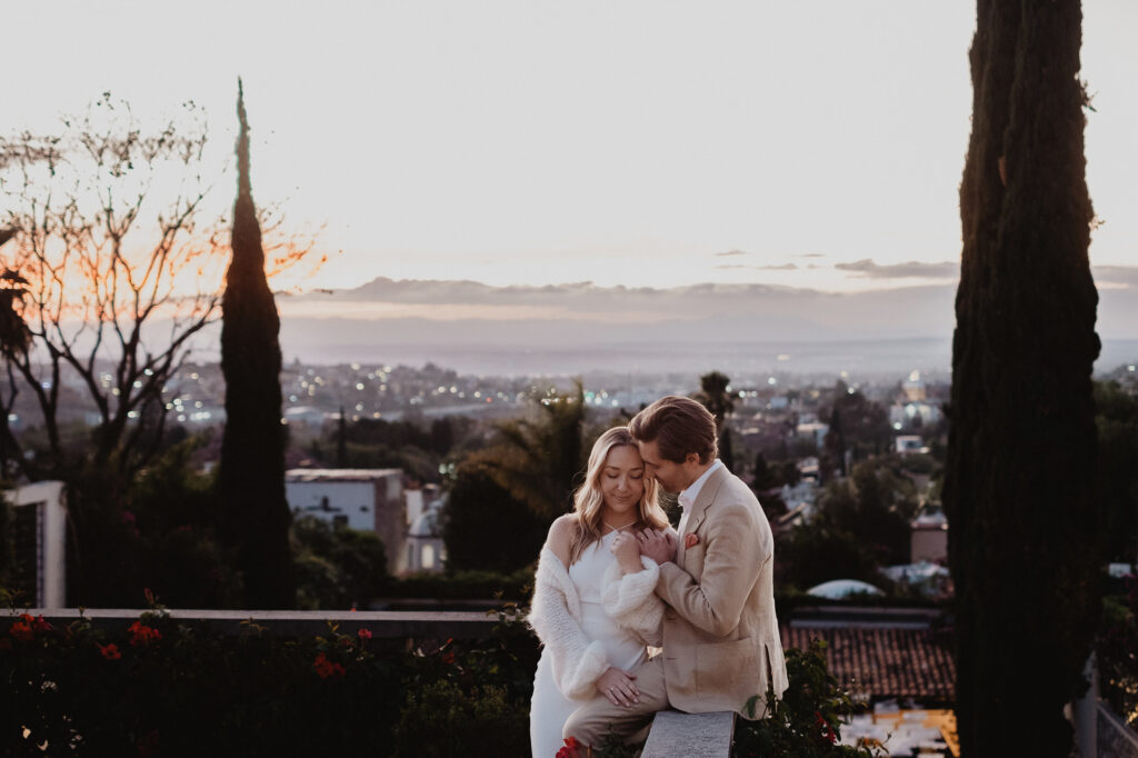 Bride and groom embrace at sunset on a terrace overlooking San Miguel de Allende during their wedding