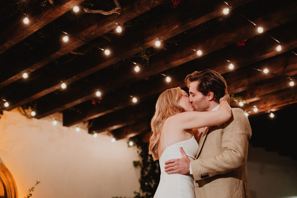 Bride and groom first kiss under string lights at San Miguel de Allende wedding reception
