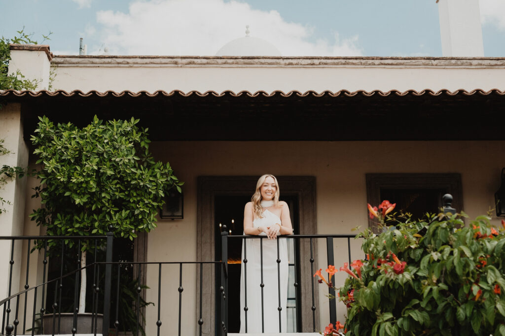 Bride in white gown smiling on balcony at San Miguel de Allende wedding venue, documentary style
