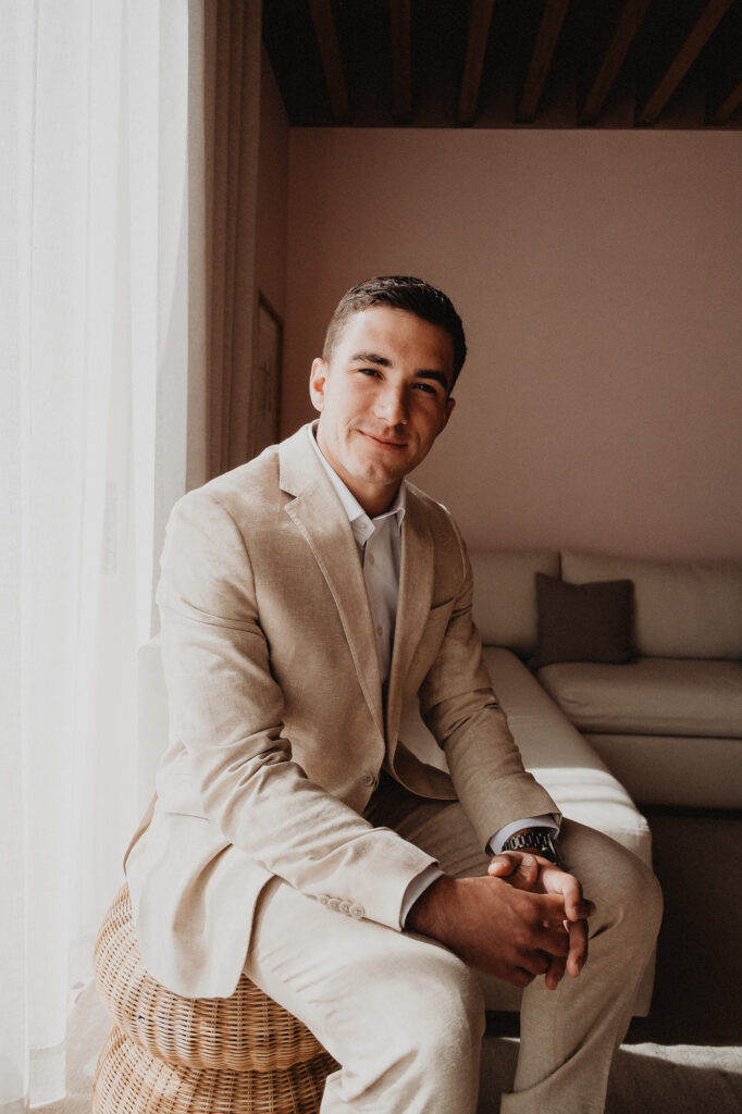 Groom in linen suit seated by window at Rosa Morada, San Pancho elopement, Mexico