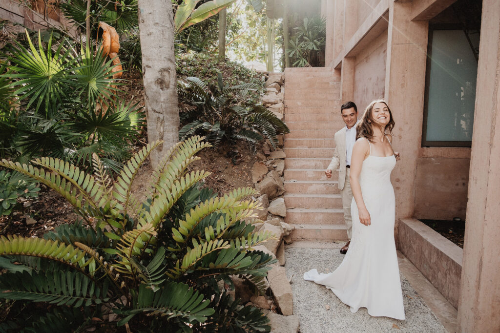 Bride laughing as groom leads her down stone steps at Rosa Morada, San Pancho elopement