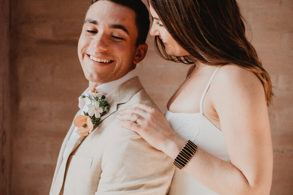 Couple laughing together during elopement in San Pancho, Mexico, groom in linen suit with floral boutonniere