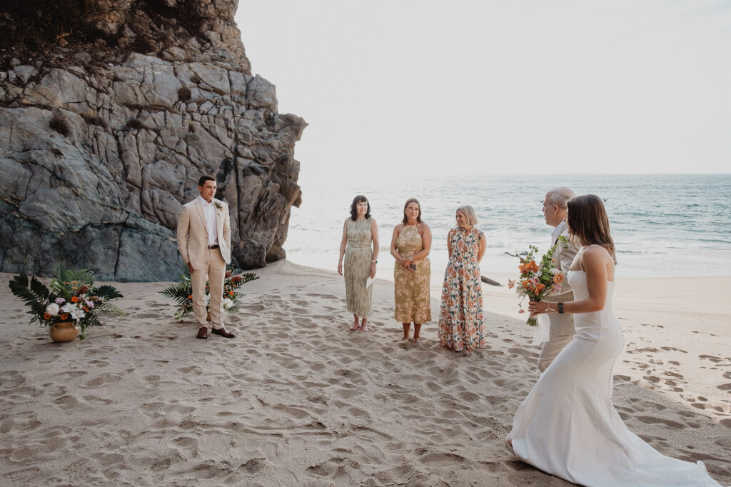 Beach elopement ceremony at Rosa Morada, San Pancho, bride walking toward groom with small group of guests