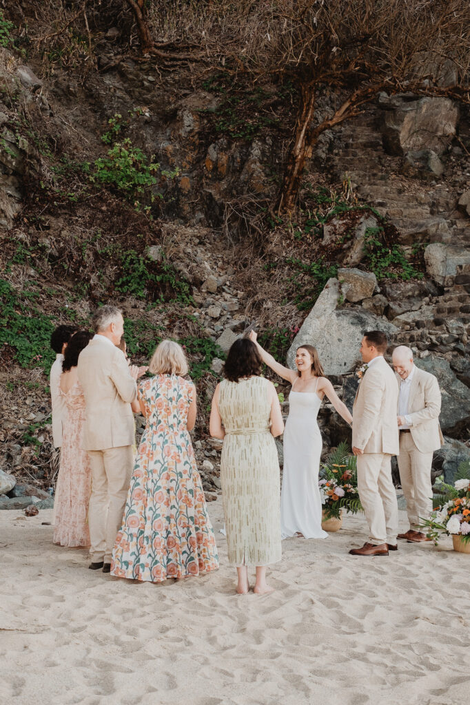 Beach elopement ceremony with small group in San Pancho Mexico, bride in white gown laughing outdoors