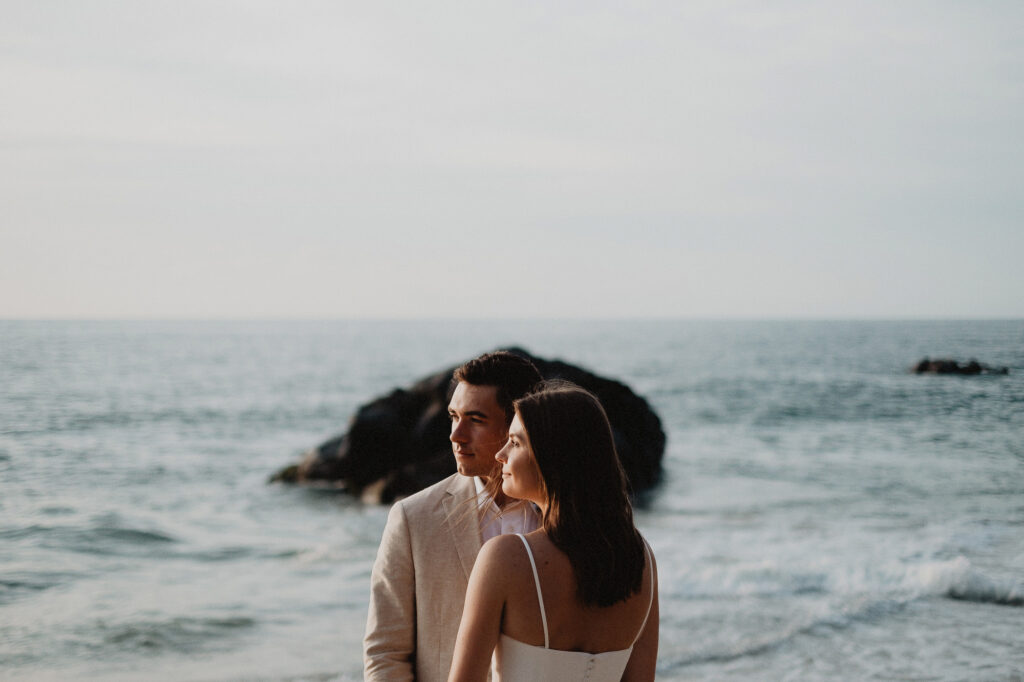 Couple during beach elopement at sunset, Rosa Morada San Pancho, Mexico, ocean rocks behind them