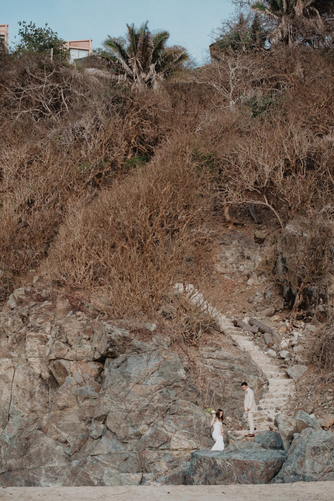 Elopement couple on rocky cliffs at Rosa Morada, San Pancho, bride in white gown, groom in tan suit