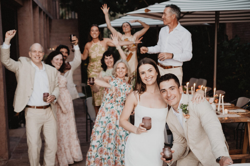 Bride and groom laughing with guests at outdoor elopement reception, San Pancho Mexico, candlelit table
