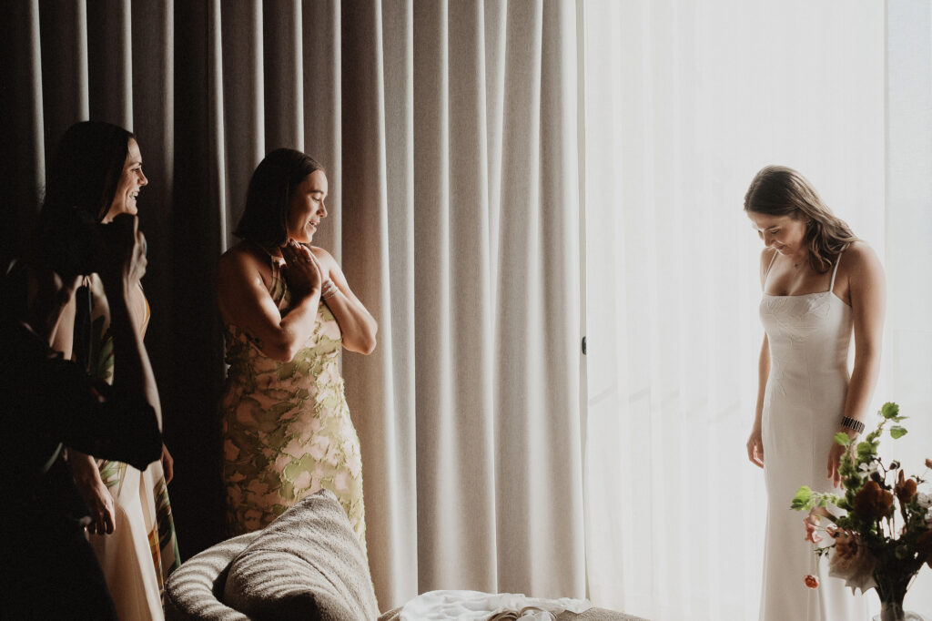 Bride in white gown laughing with bridesmaids during elopement getting ready, San Pancho Mexico