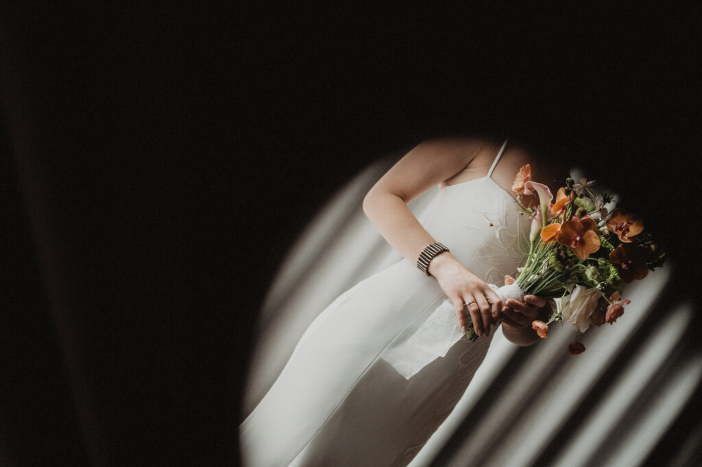 Bride in white slip dress holding vibrant bouquet during elopement, San Pancho Mexico, light through blinds