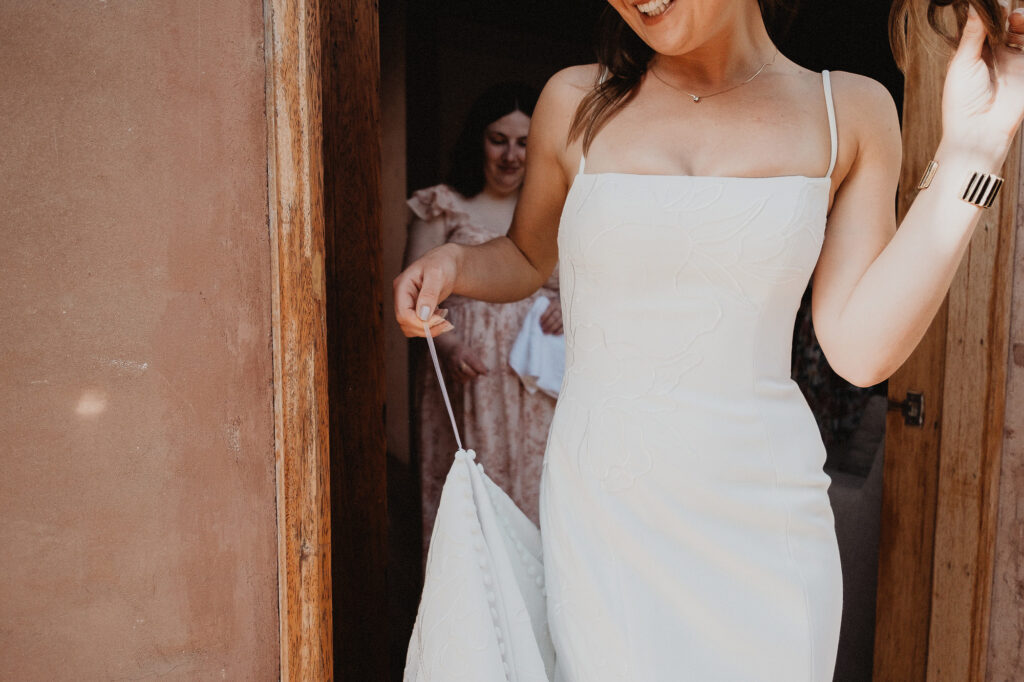 Bride in white spaghetti-strap gown laughing in doorway at Rosa Morada San Pancho elopement