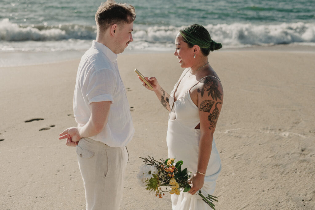 Bride reading vows from phone to groom during beach elopement at Villa Amor, Sayulita, Mexico
