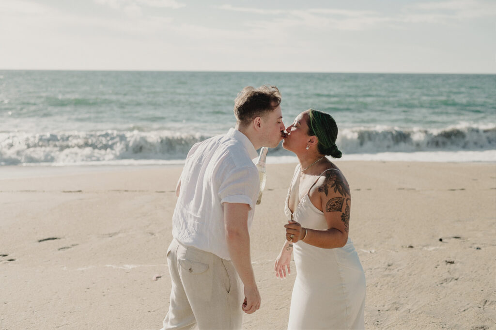 Couple sharing a champagne kiss on the beach at Villa Amor Sayulita during their elopement