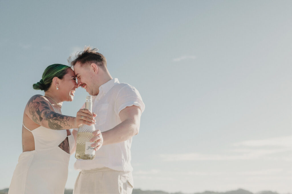 Couple laughing together during elopement at Villa Amor Sayulita Mexico holding champagne bottle