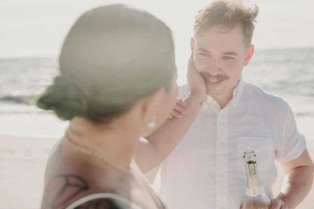Couple sharing a tender beach moment at Villa Amor Sayulita elopement, groom smiling as bride touches his face