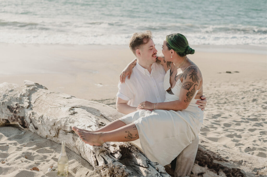 Couple sharing a tender moment on driftwood at Sayulita beach elopement, Villa Amor, Mexico