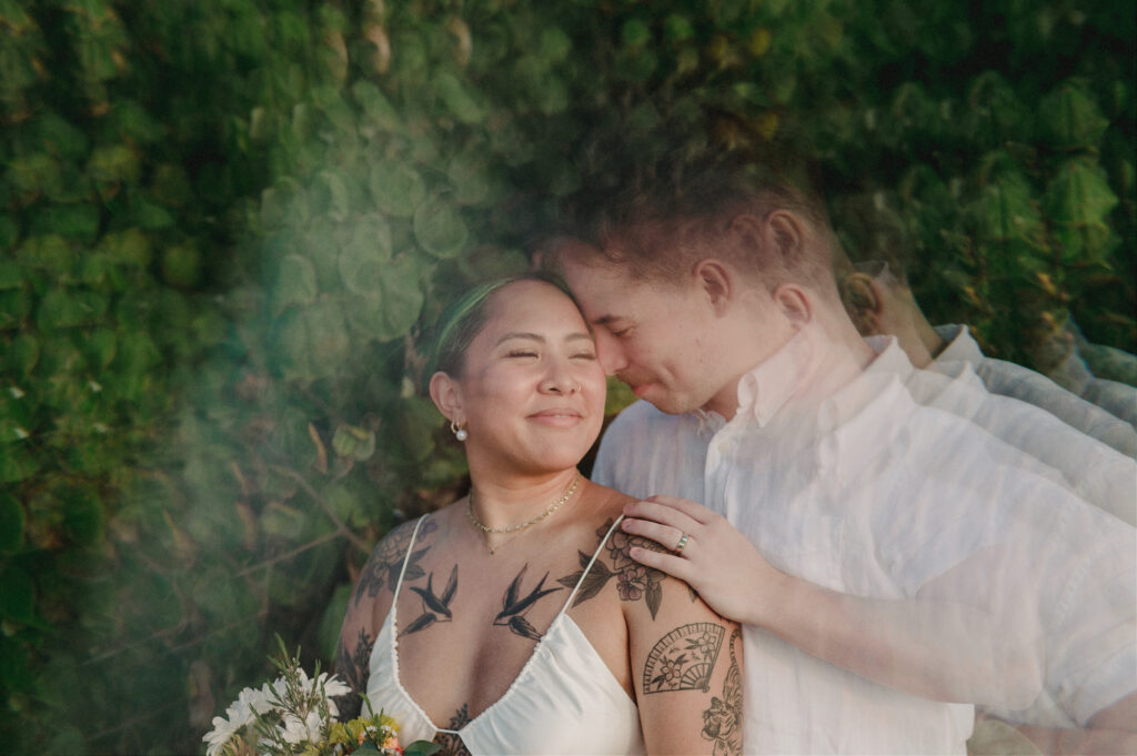 Couple sharing a tender moment during elopement at Villa Amor Sayulita, bride with tattoos holding wildflowers
