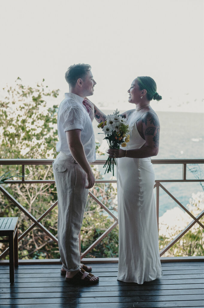 Couple sharing a joyful moment on a cliffside deck at Villa Amor Sayulita elopement, bride holding wildflower bouquet